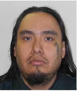Head-and-shoulders photo of a man with long dark hair, a goatee and a small tattoo near one eye, against a plain background.